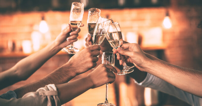 Cheers! Group of people cheering with champagne flutes with home interior in the background