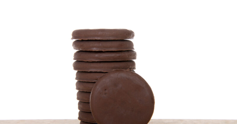 Alameda, CA - April 19, 2019: Stack of Girl Scout cookies, Thin mints, on a wood table with white background. Available annually during Girl Scout cookie sales.